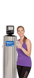A woman holding a glass of water stands next to the Waterboy 4000 SXT