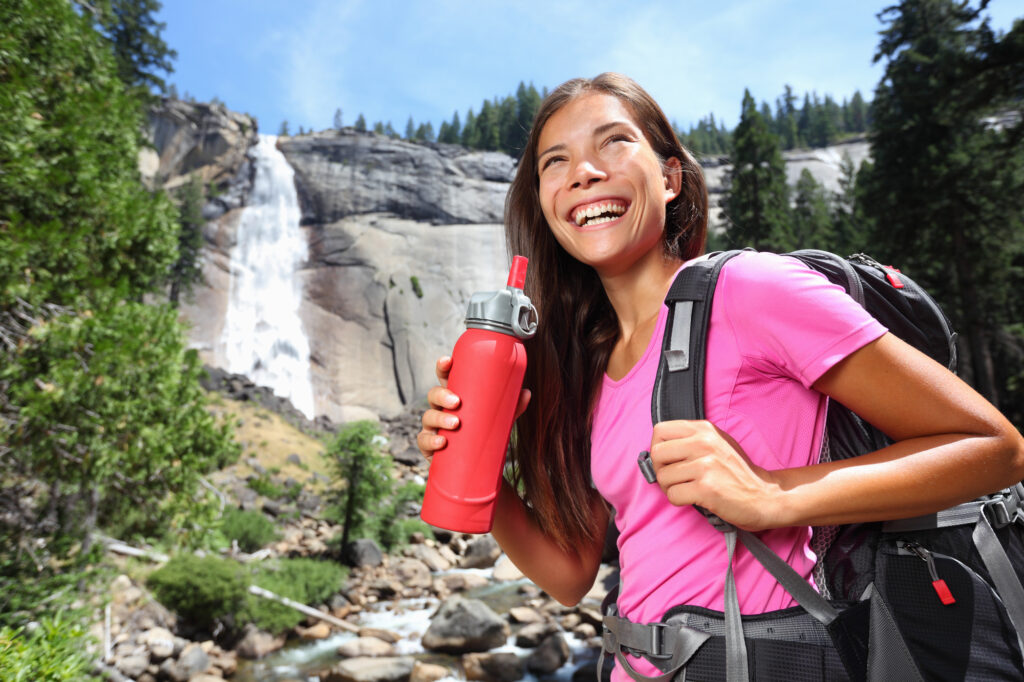Healthy hiker girl drinking water in nature hike